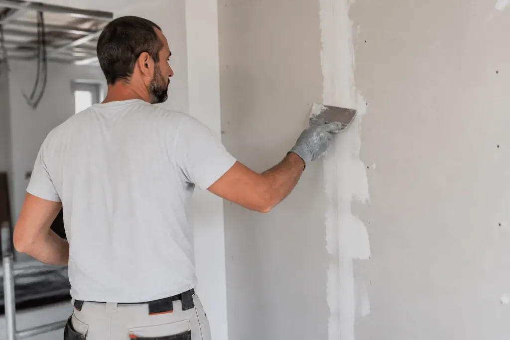 Ouvrier appliquant du composé blanc sur joint mur lisse