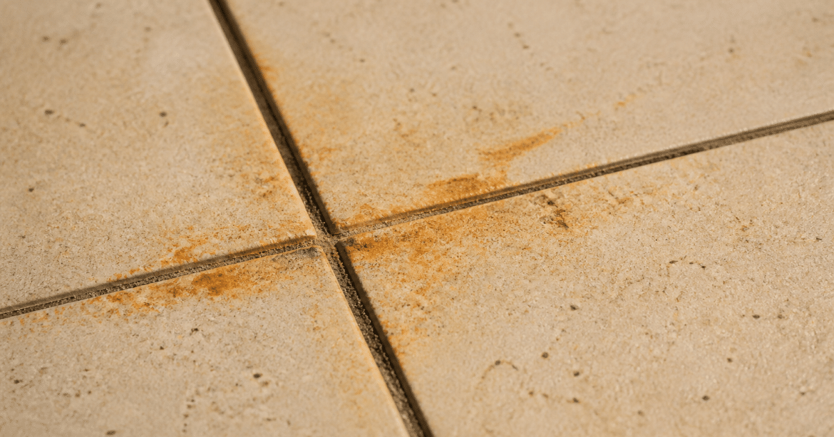 Trace orangee de rouille incrustee sur dalle carrelee beige
